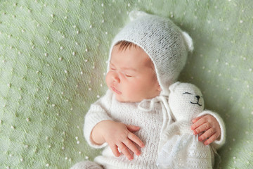 Cute sleeping newborn baby in white knitted fluffy kitten costume
