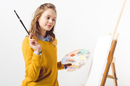 beautiful teen female painter in yellow sweater with paint brush and palette