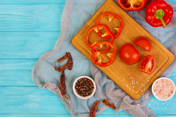 Pepper, tomato, salt, different spice on wooden background