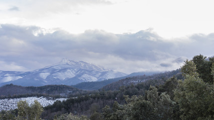 Fototapeta na wymiar Snowy peak mountains on a winter cloudscape landscape