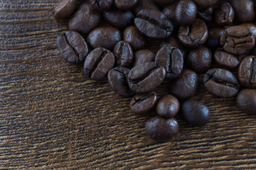 Coffee beans on a dark background and a wooden table. Closeup.