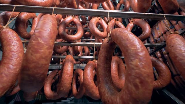 Close up of smoked sausages hanging in a storage unit with other kinds of sausages