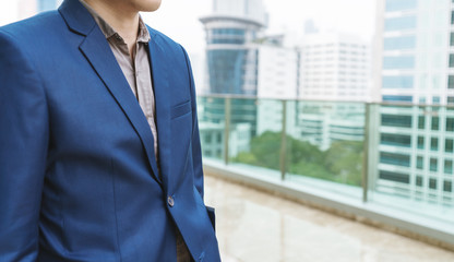 Young businessman in smart casual blue suit on skyscraper building