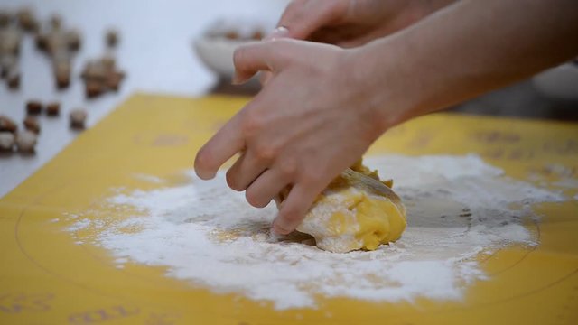 female hands in flour closeup kneading dough on table