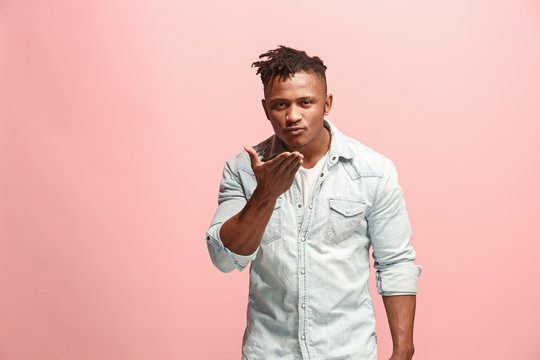 Portrait of attractive Afro-American man with air kiss isolated over pink background