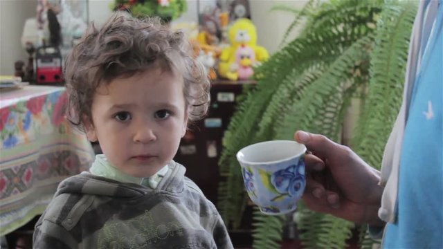 drink a little boy with tea,the father gives out a handful of tea to drink his son