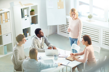 Fototapeta premium Kilku kolegów siedzi przy biurku w biurze i słucha nowych pomysłów na projekt