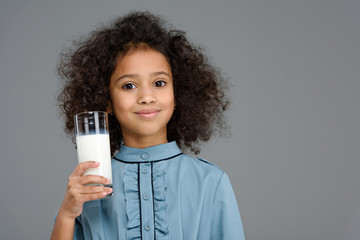 smiling little child with glass of milk isolated on grey