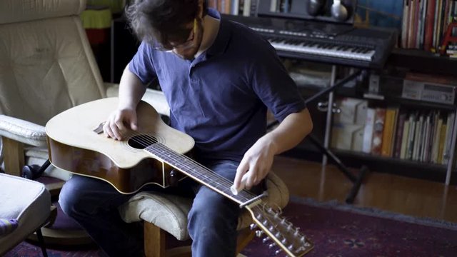 Slide guitar musician in a home environment with other instruments around.