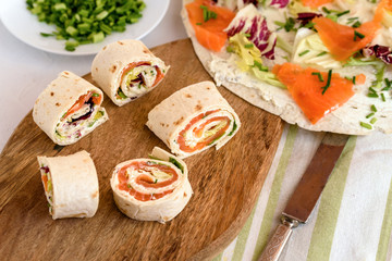 Rolls of thin pancakes with smoked salmon, cream cheese, chives and lettuce.
