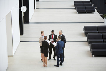 Circle of elegant business people or delegates in formalwear talking about financial rates