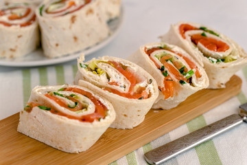 Rolls of thin pancakes with smoked salmon, cream cheese, chives and lettuce.