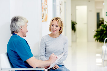 Surgeon talking with woman in corridor at hospital