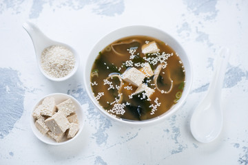 Miso soup with tofu cheese, seaweed and sesame seeds on a white concrete background, high angle view