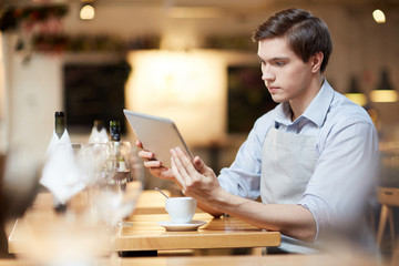 Fototapeta premium Waiter using digital tablet in cafe. He is checking orders online