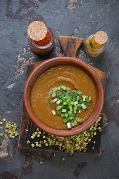 Bowl of pea soup with curry and greens cooked in south asian style, view from above, vertical shot