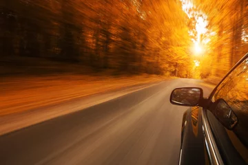 Foto auf Acrylglas Nahaufnahme eines Autos, das auf der leeren, herbstlichen Straße mit Kopierraum beschleunigt © rangizzz