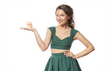 Brunette pretty beautiful caucasian woman in green festive dress showing proposing holding sweet cupcake dessert in her palms. Isolated white background