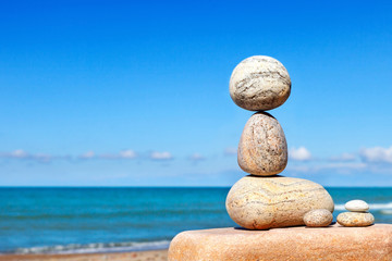 White stones balance on a background of blue sky and sea