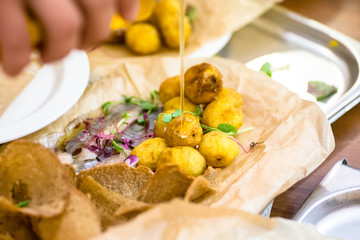 Croquettes of potatoes with herring and chips with bread lie on the paper.