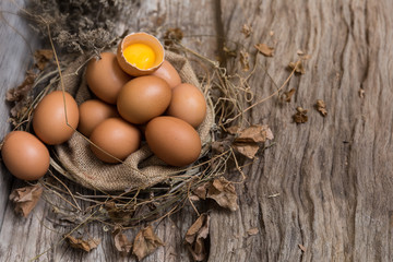 View of raw chicken egg chicken egg and broken egg in box on rustic wooden background and cover with dry grass,rope and dry leaves.