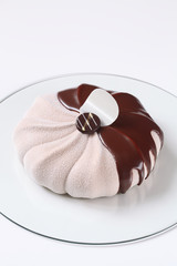 Contemporary Mousse Cake covered with Chocolate Glaze and White Velvet Spray, on white background.