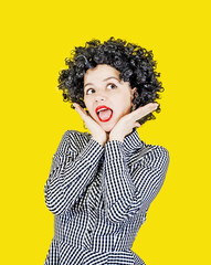 Happy girl with big black hair with an expression of surprise from the news, isolated on a yellow background