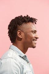 The happy business Afro-American man standing and smiling against pink background. Profile view.