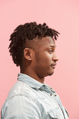 The surprised business Afro-American man standing and looking pink background. Profile view.