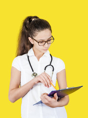 A female brunette doctor examines a medical history, isolated on a yellow background