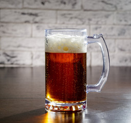 Beer with foam in glass is worth on the table.