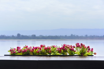 Fototapeta na wymiar Beautiful artificial roses decorated on the balcony , viewing Mekong river in the background , Nong Khai , Thailand