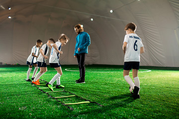 Obraz premium Team of young boys exercising on green pitch before game of professional football