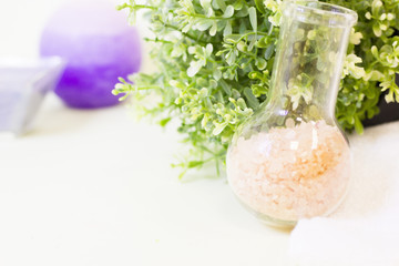 Aromatherapy spa concept. A glass bowl of orange bath salt, blue candle, green leaves, a bar of fruit soap, closeup