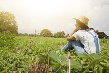 Asia women with hat sitting on meadow.