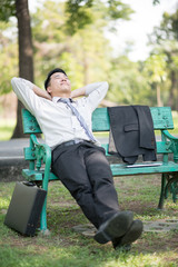 Businessperson sitting on a wooden bench and relaxing in a park