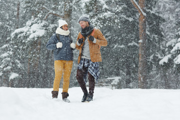 Fototapeta na wymiar Young couple of trippers in winterwear enjoying their travel on snowy winter day