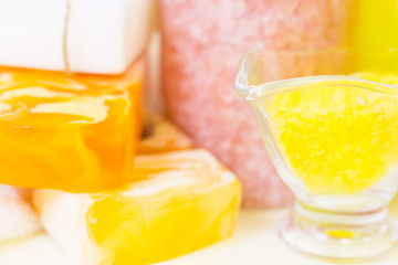 Aromatherapy spa concept. A glass bowl of orange bath salt, a bar of fruit soap, a bottle with yellow oil, white background