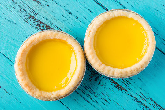 top view studio shoot of two egg tarts on a wood background