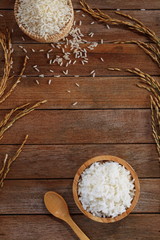 White rice cooked thai jasmine rice in wooden bowl and unmilled rice on wooden background