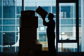 Profile outline of delivery man loading packages and putting them on top of each other
