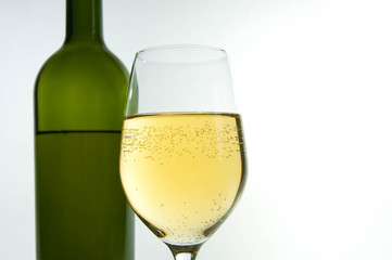 White wine in glass, green bottle in the background  isolated on white background.