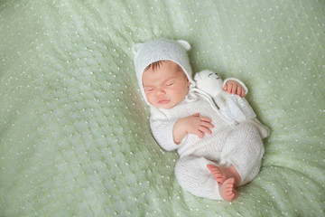 Cute sleeping newborn baby in white knitted fluffy kitten costume