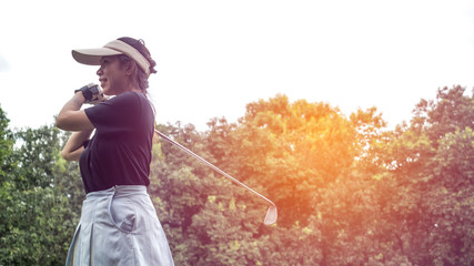 Portrait of a Asian woman golfer in black T-shirt with a golf club on a background of golf courses