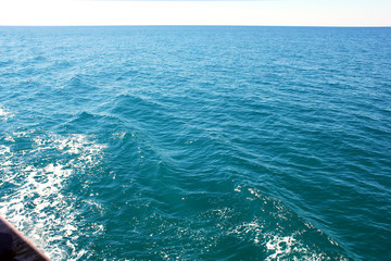 Sea waves and foam over the board of the ship. Sailing regatta in the open sea.  Boat sailing in blue Mediterranean sea in summer vacation. Recreational yacht trip on a very sunny day.