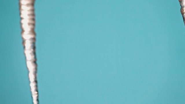 Zoom to closeup of icycles from a roof in a sunny day
