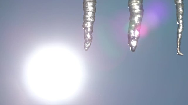 Zoom to closeup of icycles from a roof in a sunny day
