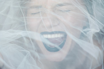 screaming face of a woman or a girl behind a veil. woman with black lips. 