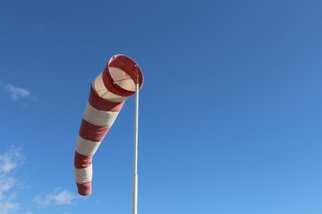 Red and white striped wind cone against blue sky