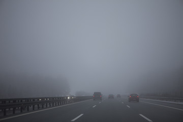 Cars driving in a highway in a foggy day.